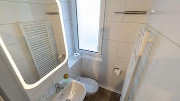 Un baño con lavamanos blanco, inodoro y espejo con luz.