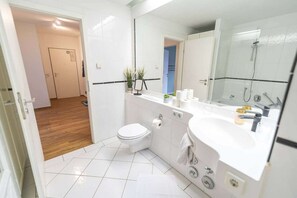 Un baño moderno con inodoro, lavamanos y ducha.