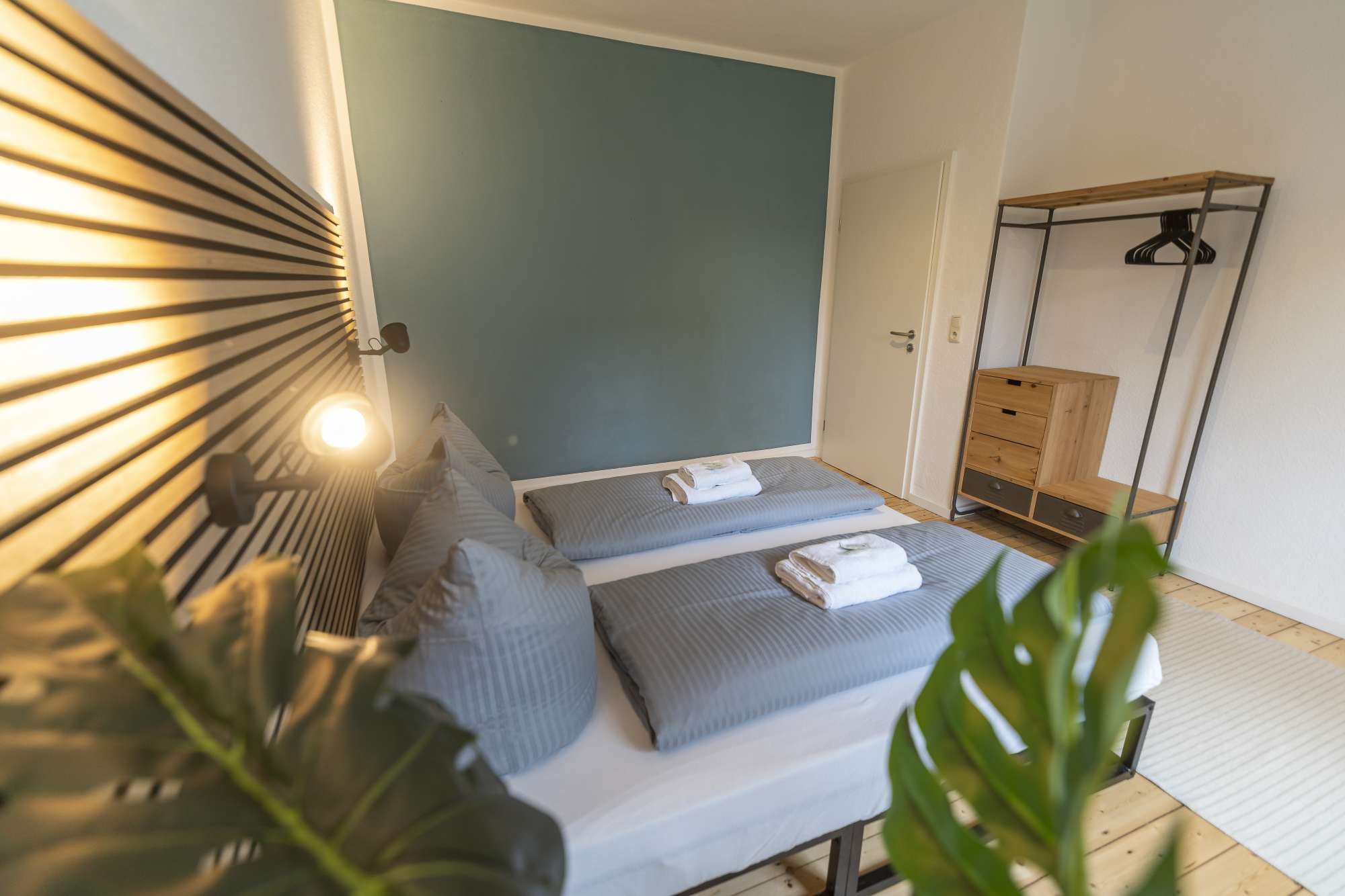 Ein Schlafzimmer mit einem Bett, Nachttischen, einem Hängekleiderschrank und einer Pflanze.