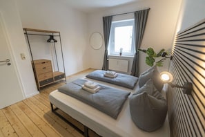 A bedroom with a bed, bedside tables, a wardrobe, a window with curtains, and a potted plant. - RR | Awesome Apartment 46 m² | Kitchen | WIFI (Magdeburg)