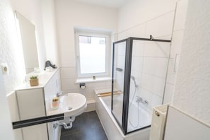 A bathroom with a white sink, a glass-enclosed shower, and a window above the sink. - RR | Awesome Apartment 46 m² | Kitchen | WIFI (Magdeburg)