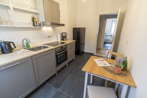 A compact kitchen with a sink, stove, refrigerator, and a dining area with a table and chairs. - RR | Awesome Apartment 46 m² | Kitchen | WIFI (Magdeburg)