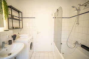 Une salle de bain équipée d’un lavabo, d’un lave-linge et d’une douche.