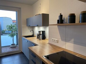 Una cuina moderna amb forn integrat, cafetera i un rentaplat.