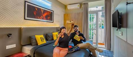 A modern hotel room with a large bed, a flat-screen TV, and a ceiling fan.