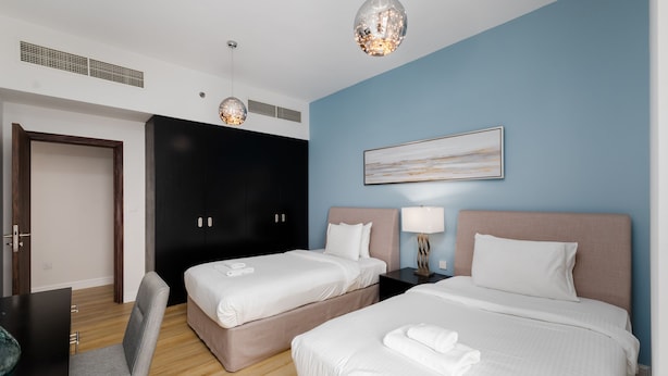 A hotel room with two beds, a desk, a chair, and a large window. - Trendy JBR 2BR w Pool and Gym Marina Views (Dubai)