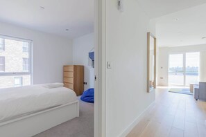 A modern bedroom with a large window, a bed, a wardrobe, and a blue bean bag chair. - Gorgeous 1BD Flat with Incredible Views of the O2 (Greater London)