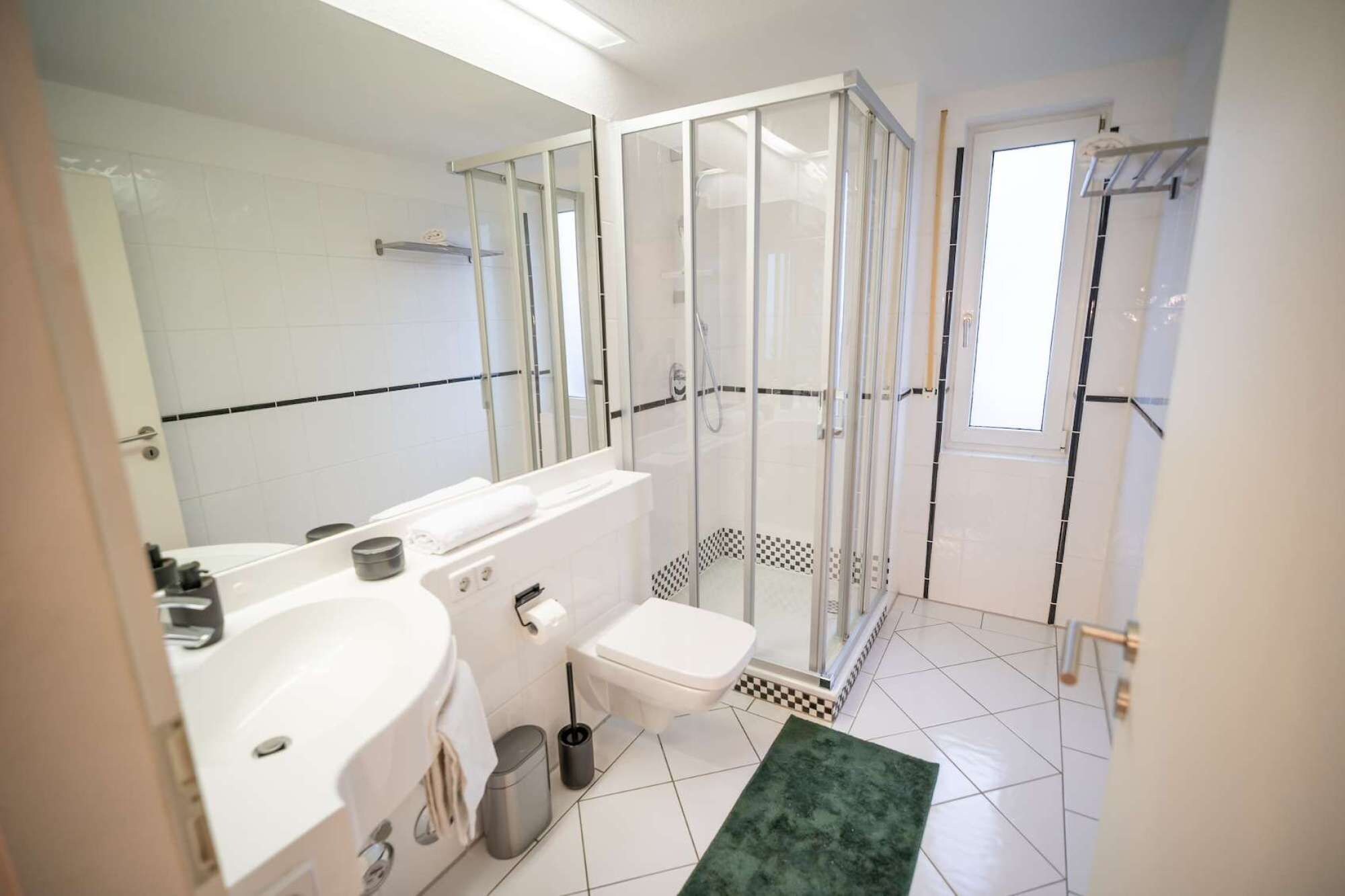 A modern bathroom with a glass-enclosed shower, a white sink, and a toilet.