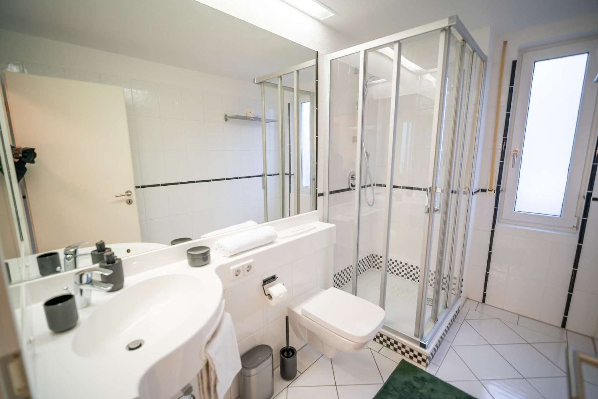 A modern bathroom with a shower enclosure, a sink, and a toilet.