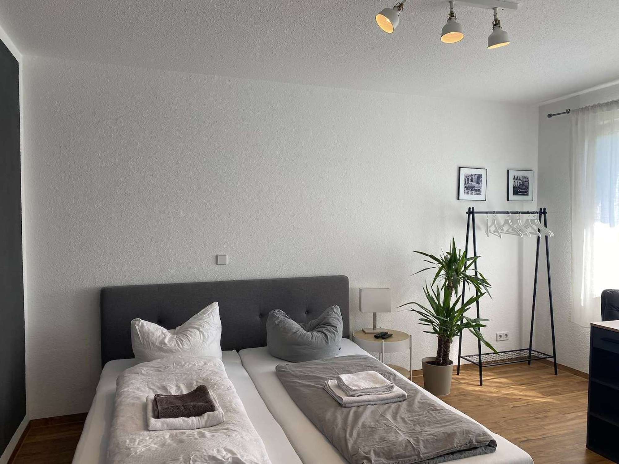 A modern bedroom with a large bed, bedside tables, a plant, and a desk with a chair.