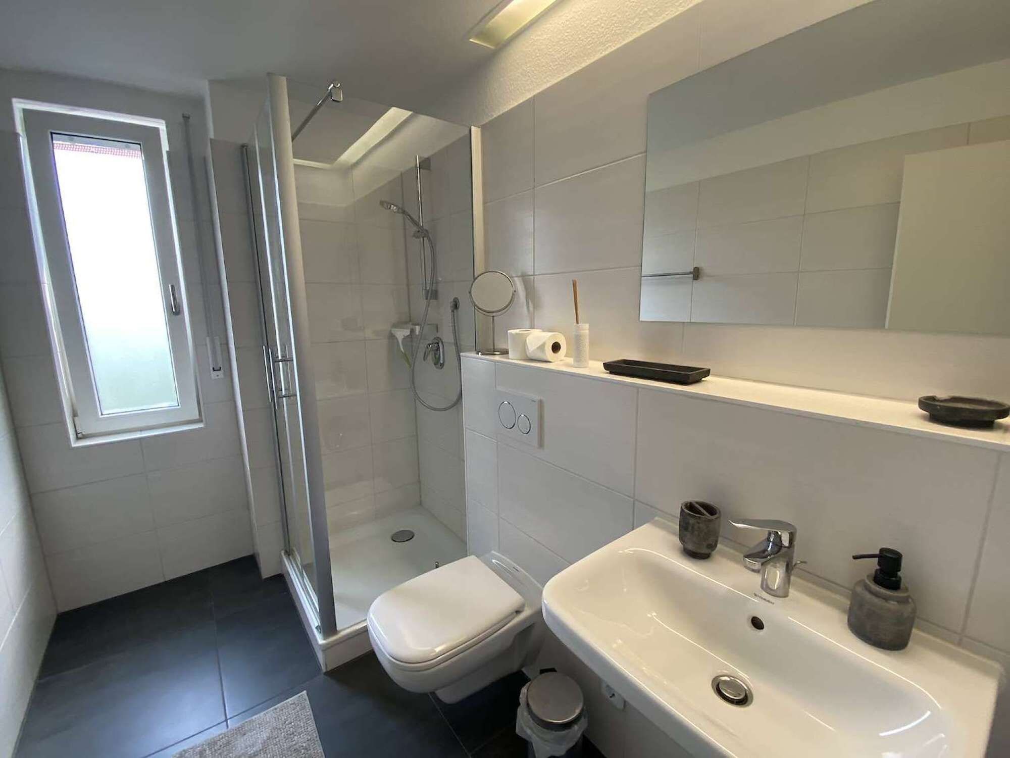 A modern bathroom with a toilet, sink, and shower.