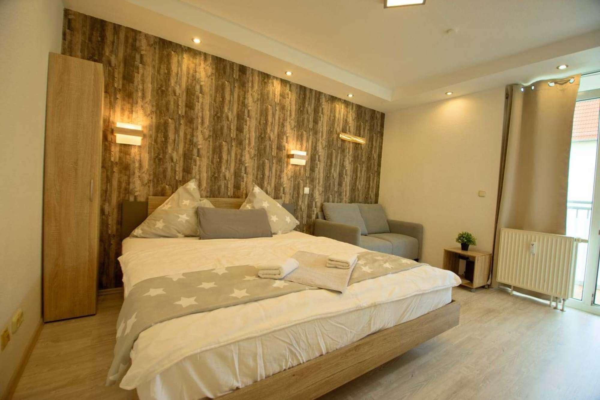 A bedroom with a bed, bedside tables, a sofa, and a radiator.