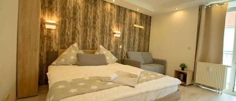 A bedroom with a bed, bedside tables, a sofa, and a radiator.