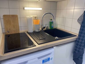 A kitchen with a Bosch induction cooktop, a sink, and a wooden cutting board. - RR | Charming Apartment - Balcony - WIFI - Kitchen (Magdeburg)