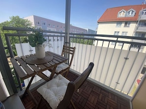 A balcony with a table, chairs, and a potted plant. - RR | Charming Apartment - Balcony - WIFI - Kitchen (Magdeburg)