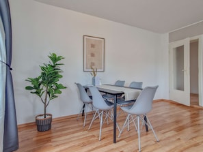 A dining area with a table and chairs, a potted plant, and a framed artwork on the wall. - RR | Apartments Kappel | 85 m² | Lift | WIFI (Chemnitz)