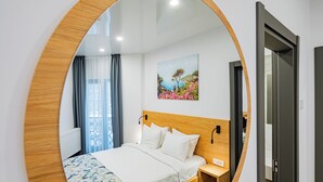 A modern hotel room with a wooden headboard, a bed with a patterned bedspread, a bedside table, and a painting of a landscape on the wall. - Q Villa (Sacele)