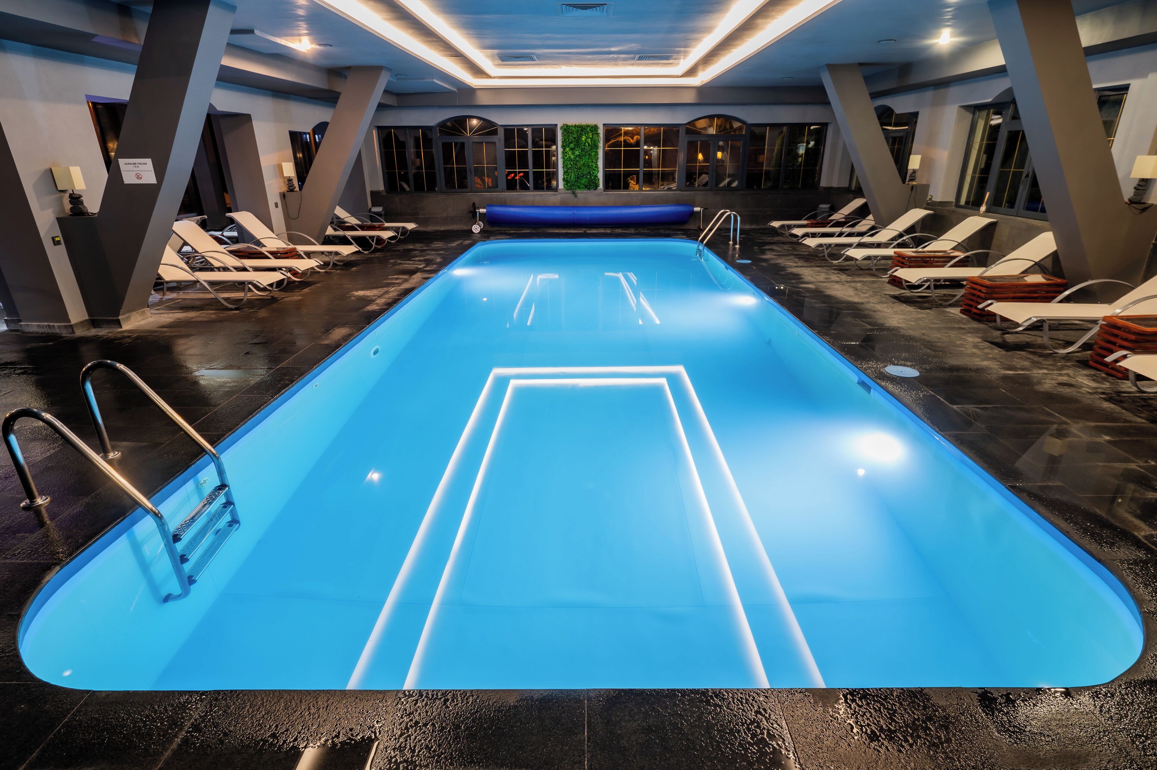 A swimming pool with lounge chairs and a blue floor.