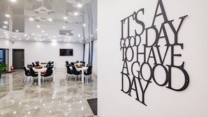 A modern dining area with a polished floor and contemporary furniture. A motivational wall art with the phrase "It's a good day to have a good day" is visible. - Q Villa (Sacele)