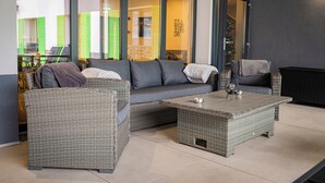 A modern lounge area with wicker furniture, a glass door leading to a bright room, and a sign reading "It's a day to be good." - Q Villa (Sacele)