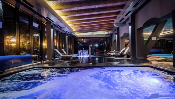 A spa area with a hot tub, lounge chairs, and a view of the outdoors. - Q Villa (Sacele)