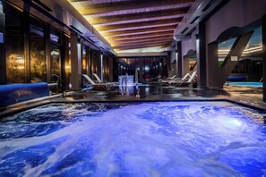 A spa area with a hot tub, lounge chairs, and a view of the outdoors. - Q Villa (Sacele)