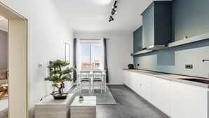 A modern kitchen with white cabinets, a built-in oven, and a window overlooking a cityscape. - Modern Apartment With Scenic Views Earthy Vibes (Shkodër)