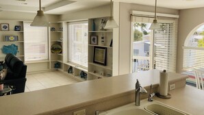 A modern kitchen with a large island, pendant lights, and a view of the outside through large windows.