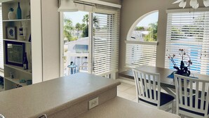 A kitchen with a granite countertop, white cabinetry, and a dining area with a white table and chairs.