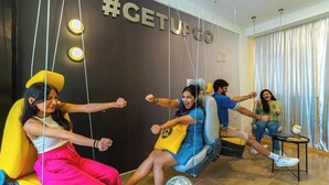 A room with a #GETUPGO sign, a disco ball, and people on swings. - The Hosteller Bangalore, Koramangala (Karnataka)
