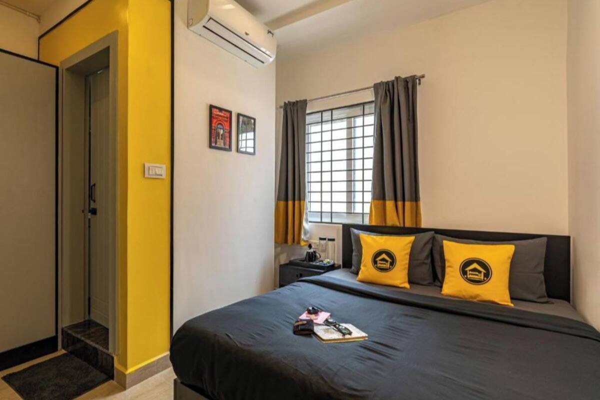Une chambre d’hôtel avec un lit, une table de chevet, une fenêtre avec des rideaux et une porte.