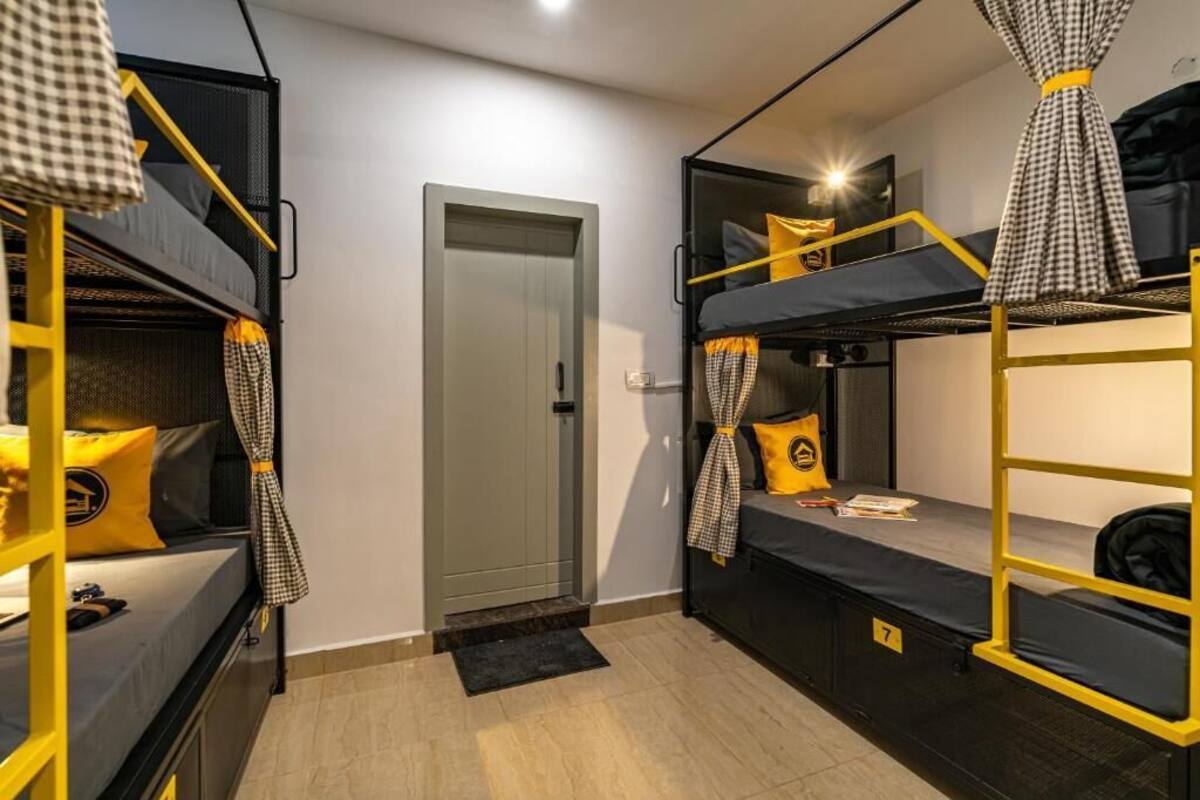 Une petite pièce avec des lits superposés, une porte et une petite table accompagnée d’une chaise.
