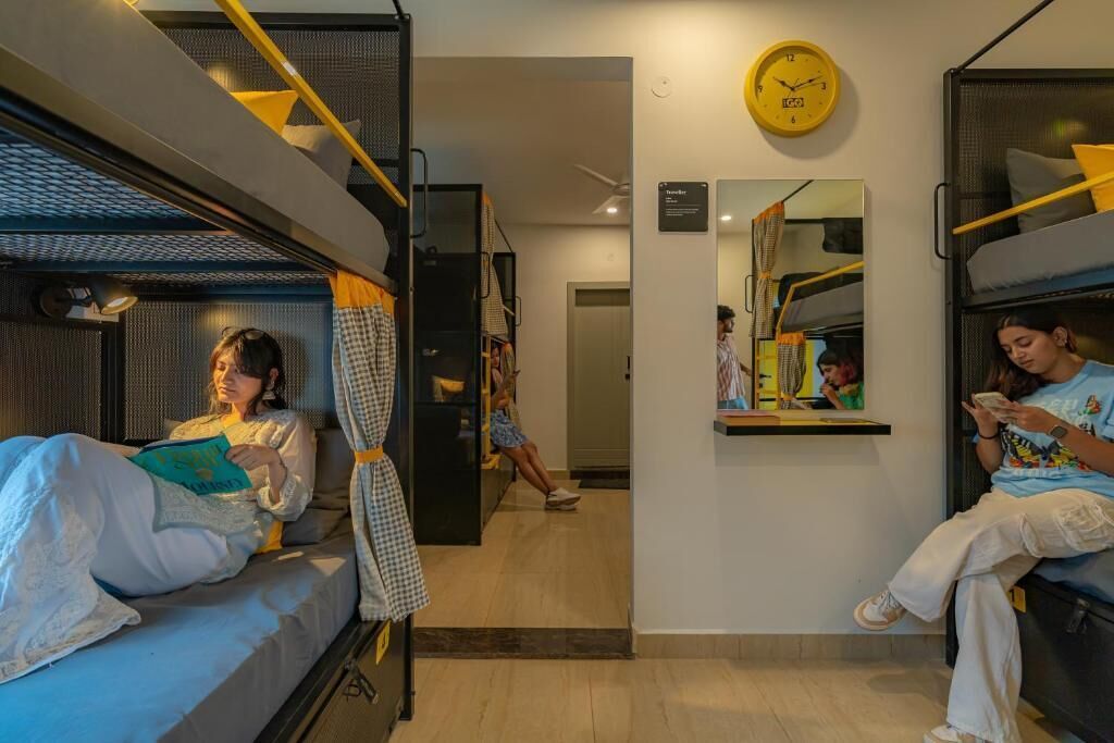 Ein kleines Hotelzimmer mit Etagenbetten, einem kleinen Spiegel und einer Wanduhr.