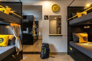 A compact hotel room with bunk beds, a small desk, a mirror, and a clock on the wall. - The Hosteller Bangalore, Koramangala (Karnataka)