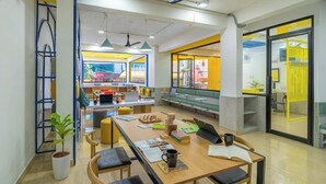 A modern office space with a long table, chairs, and a seating area with a view. - The Hosteller Bangalore, Koramangala (Karnataka)