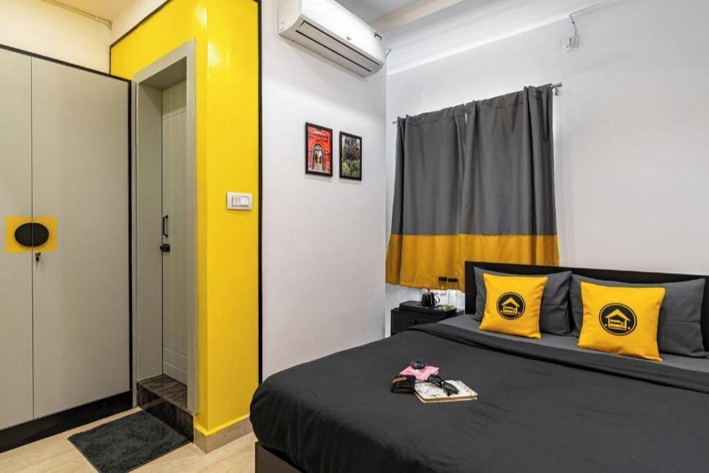 A hotel room with a bed, a wardrobe, a nightstand, and a window with curtains.