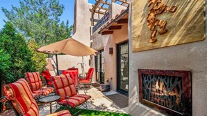 An outdoor patio with striped red and orange chairs, a round table, and a beige umbrella.