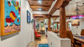 A hallway with a wooden ceiling, a colorful mural, and a dining area with a table and chairs.