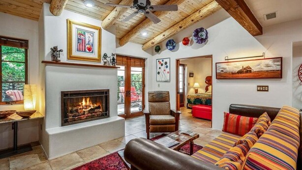 A living room with a fireplace, a ceiling fan, and a sofa with striped cushions.