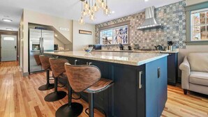 Een moderne keuken met een groot eiland, barstoelen en een koffiebar.