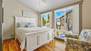 Een slaapkamer met een groot bed, een plafondventilator en uitzicht op het landschap door een schuifdeur.