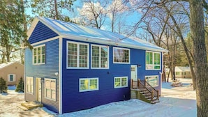Una casa azul de dos pisos con un porche cubierto y una pequeña terraza.