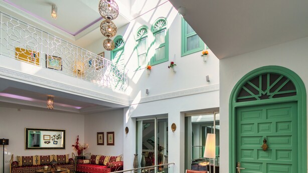 A spacious indoor area with a pool, a green door, and a red patterned carpet.