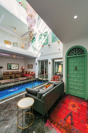 A spacious indoor area with a pool, a green door, and a red patterned carpet. - ryad ab sarai  (Chefchaouen)