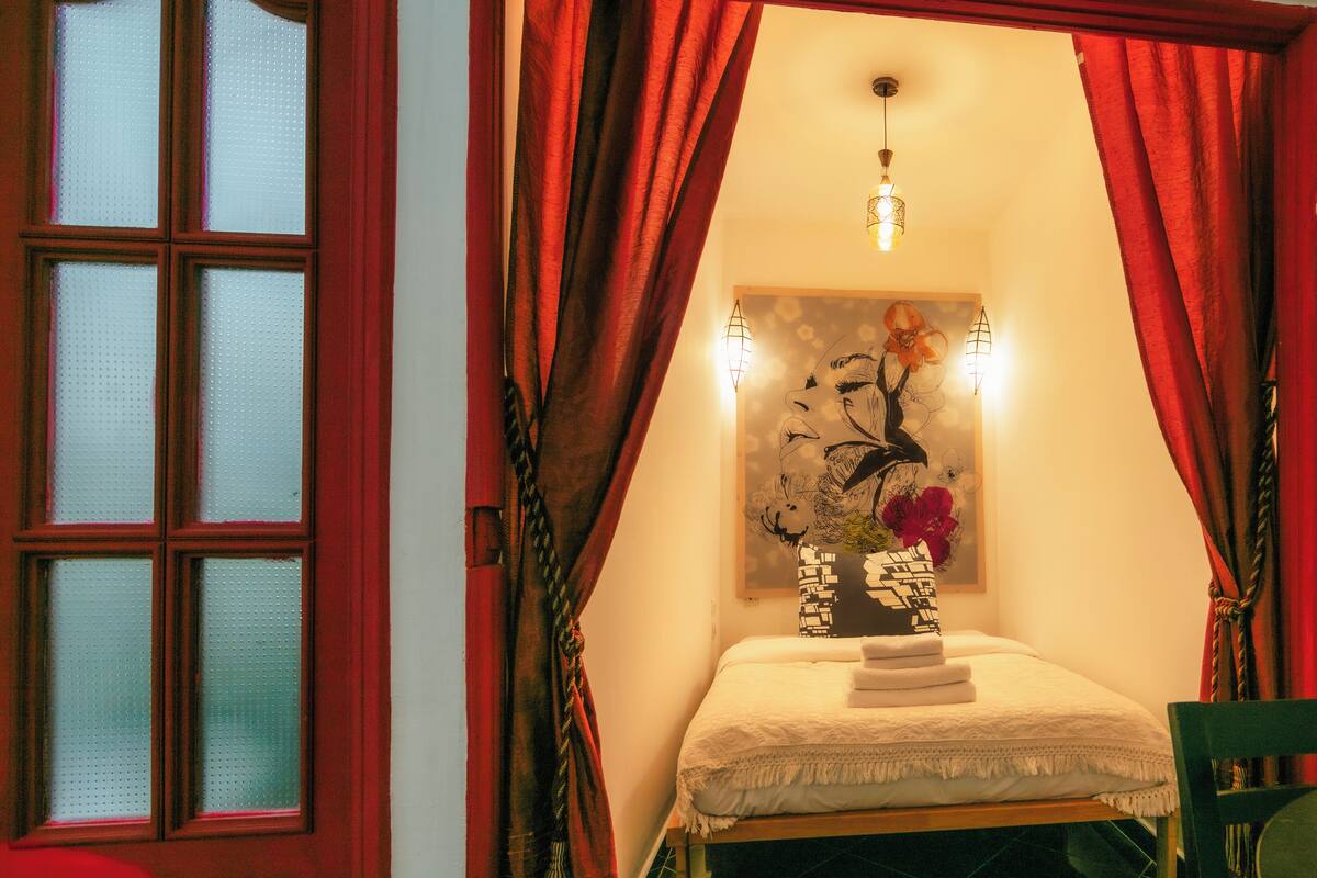 A room with a bed, a painting, and a window with curtains.