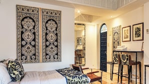 A hotel room with a large bed, a desk, and a chair. There are decorative wall panels and a chandelier.