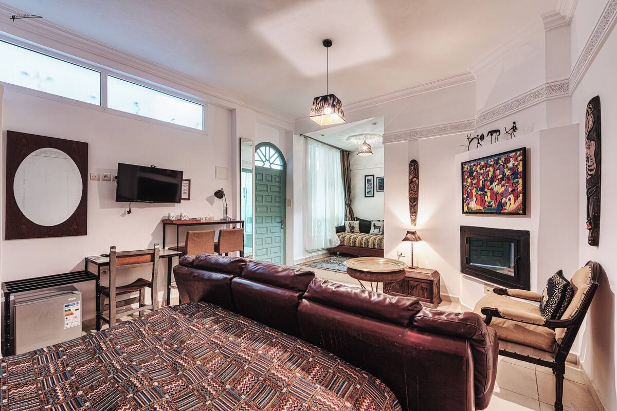 A spacious room with a large bed, a television, a fireplace, and a view of the outside.