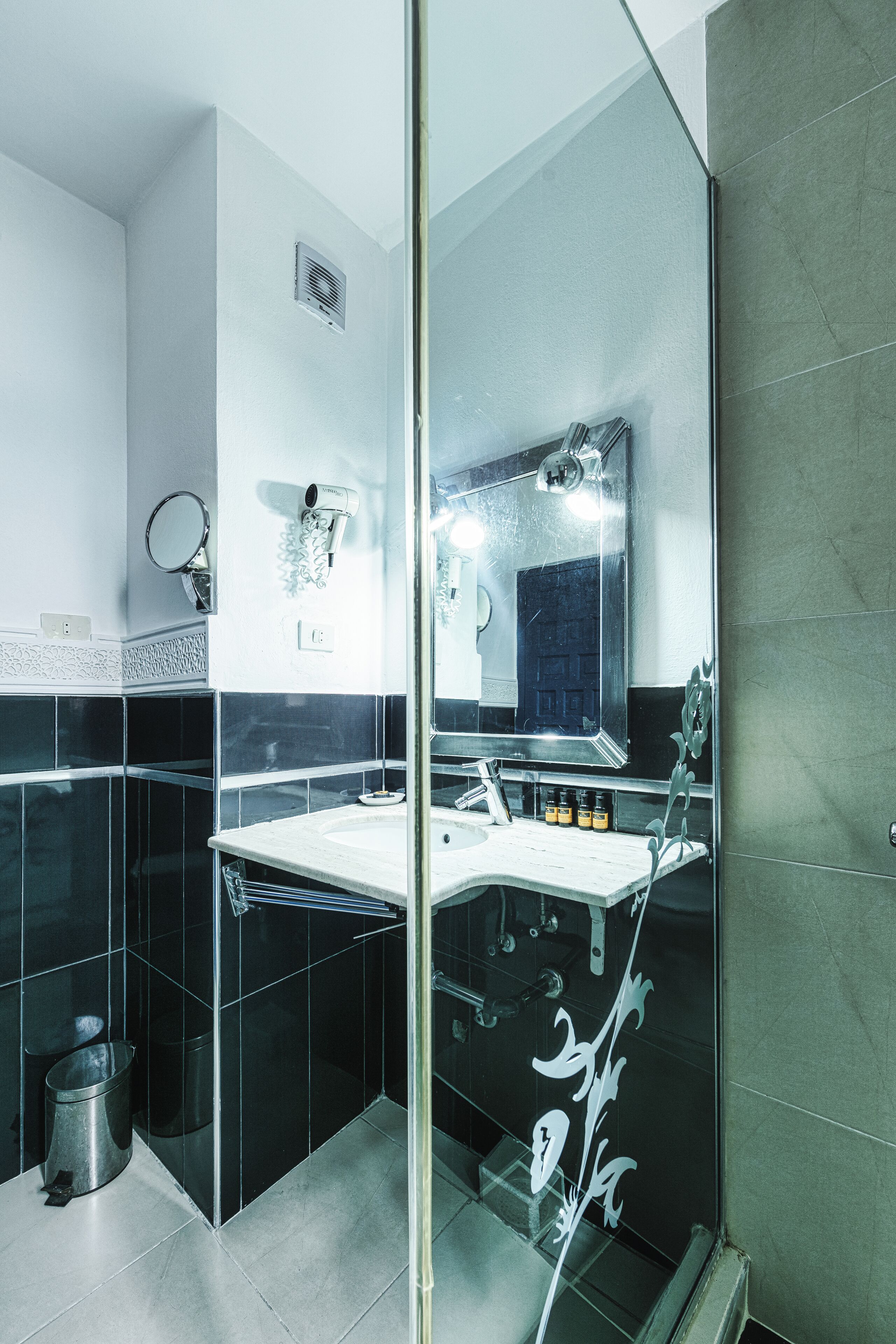 A modern bathroom with a glass shower enclosure, a large mirror, and a vanity with a sink.
