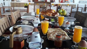 A breakfast table with croissants, eggs, juice, and Danone yogurt.