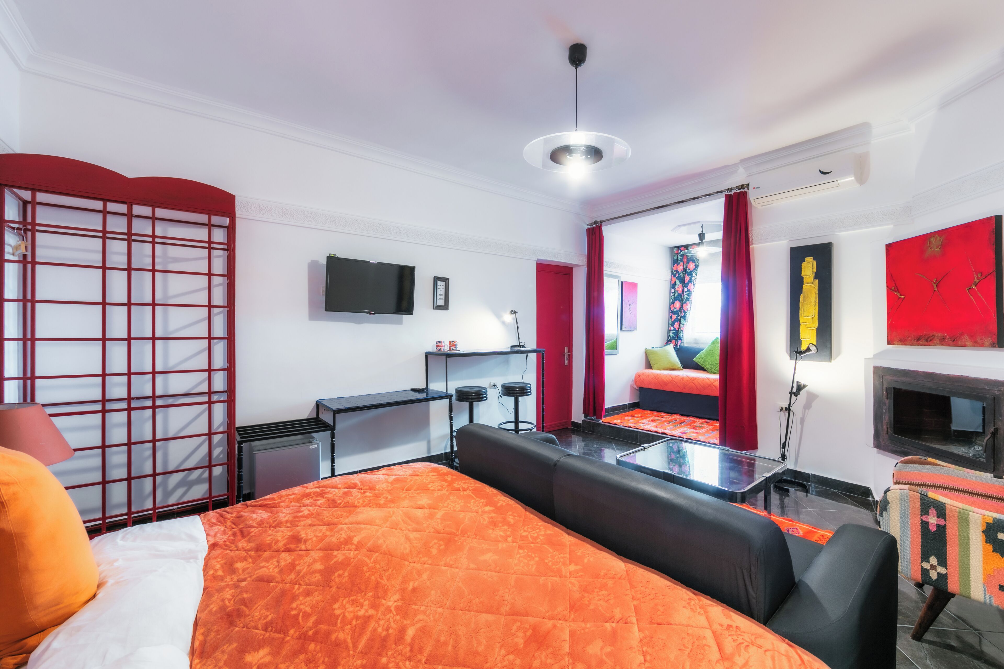 Una habitación de hotel moderna con una cama grande, un escritorio, un televisor y un sofá.